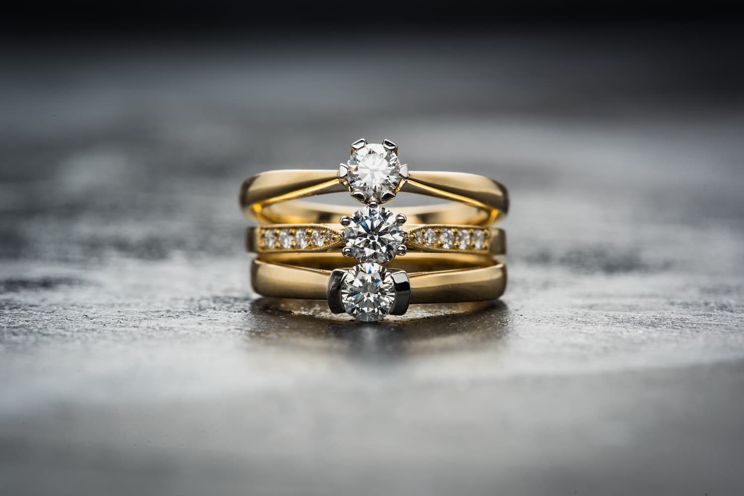 Three gold diamond rings photographed sharply against a softly blurred background