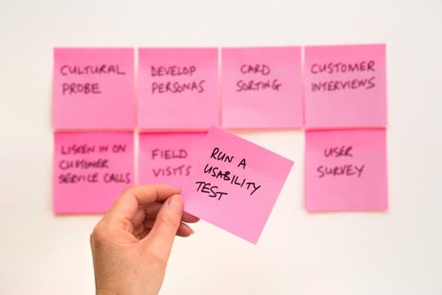 Hand holding a usability test sticky note beside other customer research methods