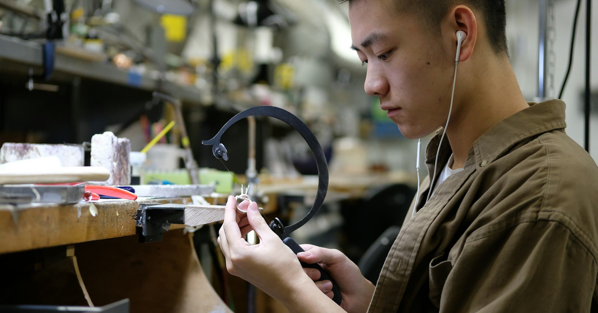 A jeweler cuts a ring with a saw at the workbench
