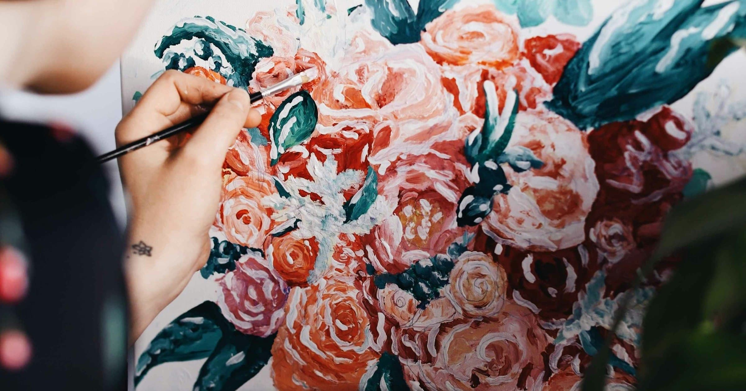 An artist paints a floral canvas